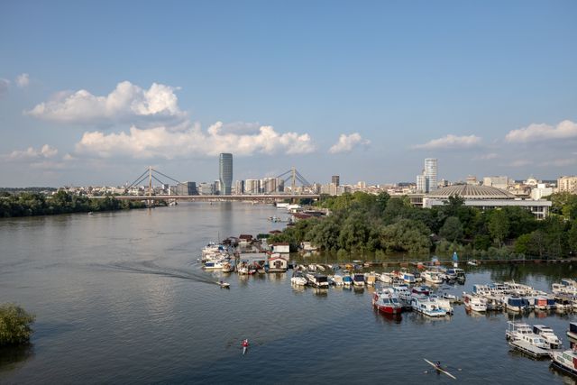 Reka sa privezanim čamcima i veslačem ispred gradske panorame