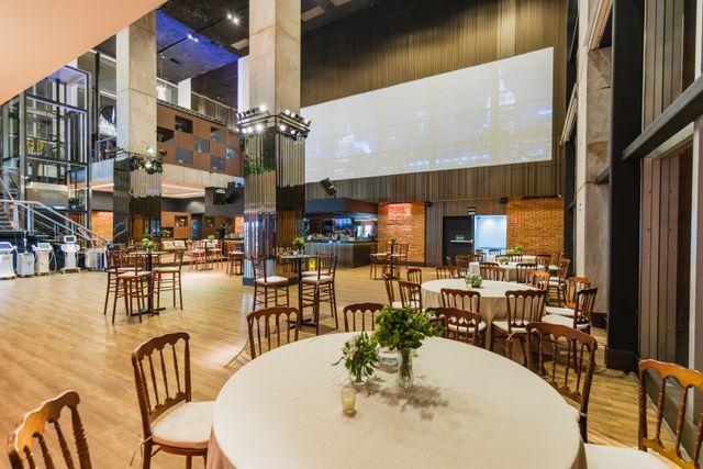 Prostrana sala za događaje sa okruglim stolovima i šankom
