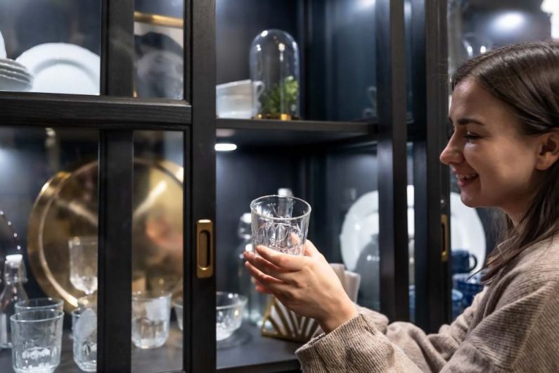 zena drzi casu za viski uruci ispred vitrine