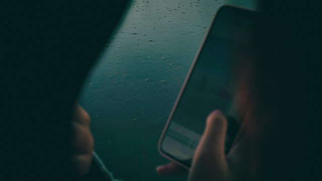 Ruke drže telefon iznad površine sa kapljicama